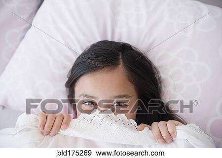 Stock Photo - Girl peeking out from bed blankets. Fotosearch