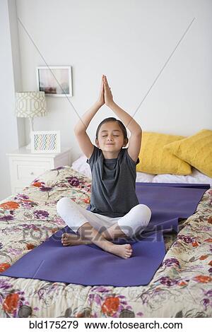 Stock Photo - Girl practicing yoga on bed. Fotosearch