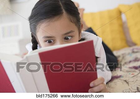 Stock Photograph - Girl reading book on bed. Fotosearch