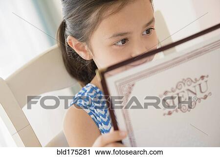 Stock Image - Girl reading menu in restaurant. Fotosearch