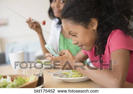 Girl using cell phone at dinner View Large Photo Image Stock Image - Girl using cell phone at dinner. Fotosearch