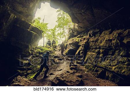 Stock Photograph - Hikers exploring rock cave. Fotosearch