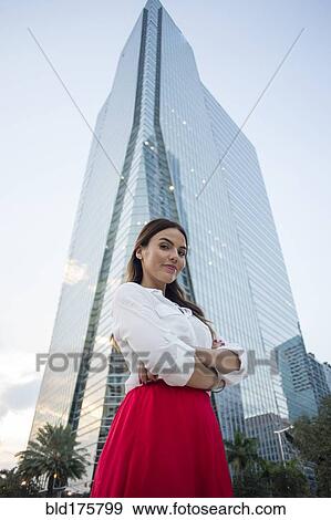 Stock Photo - Hispanic businesswoman standing near highrise. Fotosearch