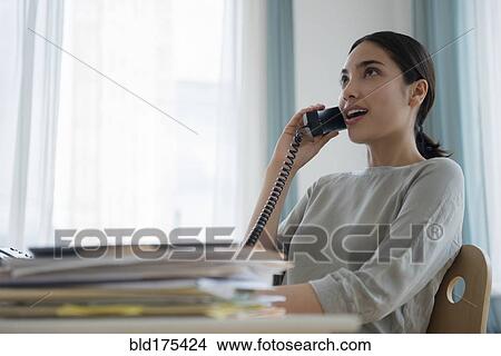 Picture - Hispanic businesswoman talking on telephone. Fotosearch