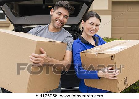 Hispanic couple carrying cardboard boxes near car View Large Photo Image Stock Photograph - Hispanic couple carrying cardboard boxes near car. Fotosearch