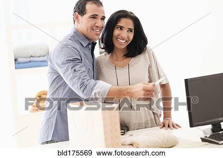 Hispanic couple paying at register View Large Photo Image Stock Photo - Hispanic couple paying at register. Fotosearch