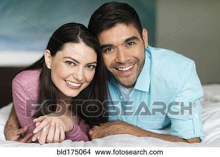 Picture - Hispanic couple smiling on bed. Fotosearch