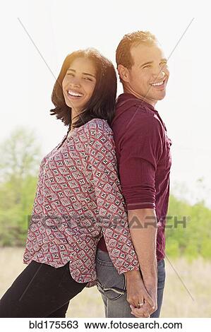 Stock Image - Hispanic couple standing back to back. Fotosearch
