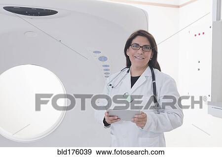 Stock Photo - Hispanic doctor standing in MRI room. Fotosearch