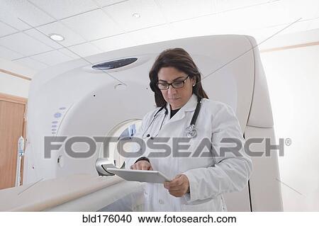 Hispanic doctor using digital tablet in MRI room View Large Photo Image Stock Image - Hispanic doctor using digital tablet in MRI room. Fotosearch