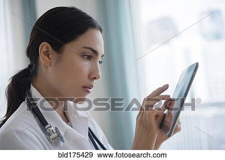 Stock Photo - Hispanic doctor using digital tablet. Fotosearch