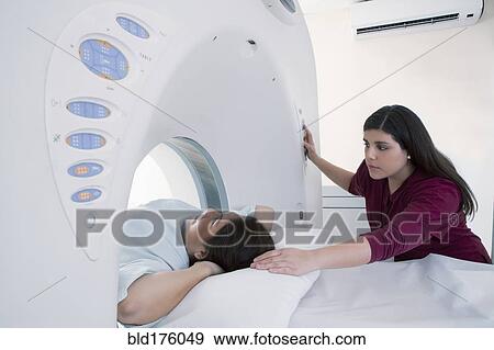Hispanic nurse examining patient in MRI machine View Large Photo Image Stock Photo - Hispanic nurse examining patient in MRI machine. Fotosearch