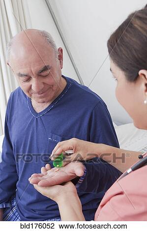 Stock Image - Hispanic nurse giving patient medication. Fotosearch