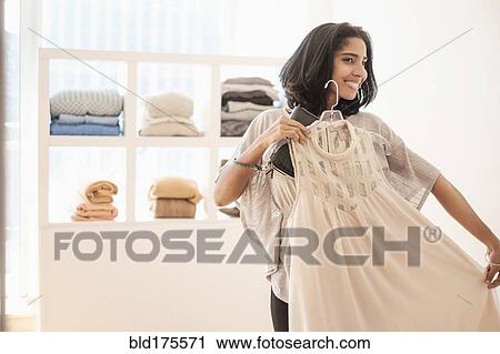 Hispanic woman admiring clothing in store View Large Photo Image Stock Image - Hispanic woman admiring clothing in store. Fotosearch