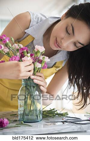 Stock Image - Hispanic woman arranging bouquet of flowers. Fotosearch