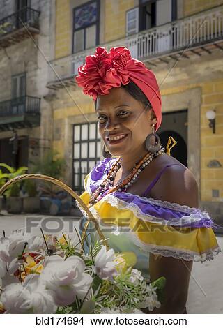 Picture - Hispanic woman carrying basket of flowers. Fotosearch