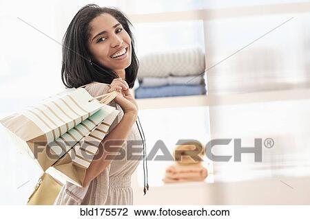 Stock Image - Hispanic woman carrying shopping bags. Fotosearch