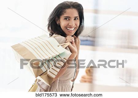 Stock Image - Hispanic woman carrying shopping bags. Fotosearch