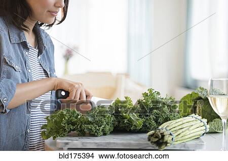 Picture - Hispanic woman chopping salad greens. Fotosearch