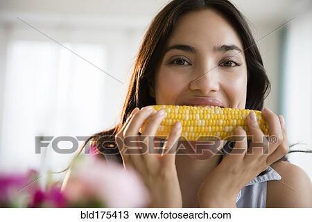 Stock Image - Hispanic woman eating corn on the cob. Fotosearch