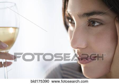 Stock Image - Hispanic woman examining glass of wine. Fotosearch