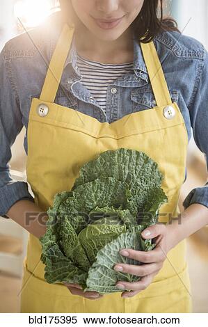 Stock Photography - Hispanic woman holding head of lettuce. Fotosearch
