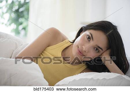 Stock Image - Hispanic woman laying in bed. Fotosearch