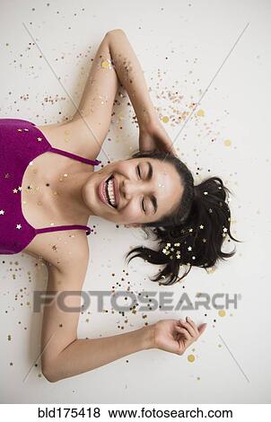 Stock Photo - Hispanic woman laying in confetti. Fotosearch