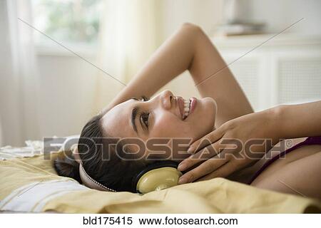 Stock Photography - Hispanic woman listening to headphones. Fotosearch