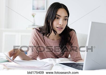 Hispanic woman paying bills on laptop View Large Photo Image Stock Photo - Hispanic woman paying bills on laptop. Fotosearch