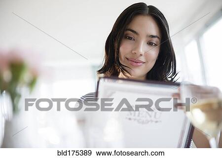 Stock Photo - Hispanic woman reading menu. Fotosearch