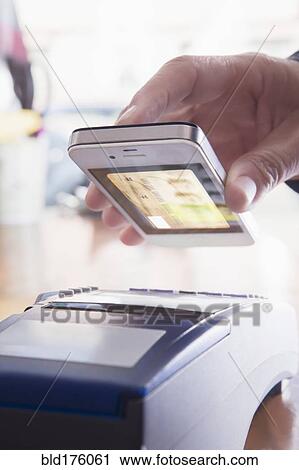 Stock Image - Hispanic woman scanning credit card from cell phone. Fotosearch