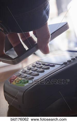 Stock Image - Hispanic woman scanning credit card from cell phone. Fotosearch