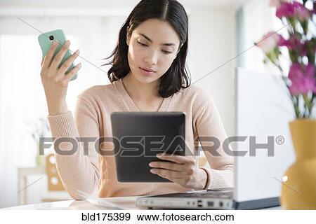 Hispanic woman using cell phone and digital tablet View Large Photo Image Stock Photo - Hispanic woman using cell phone and digital tablet. Fotosearch