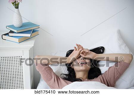 Stock Image - Hispanic woman waking up in bed. Fotosearch