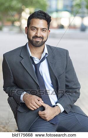 Stock Photo - Indian businessman sitting on bench in city. Fotosearch