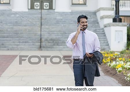 Indian businessman talking on cell phone on sidewalk View Large Photo Image Stock Image - Indian businessman talking on cell phone on sidewalk. Fotosearch