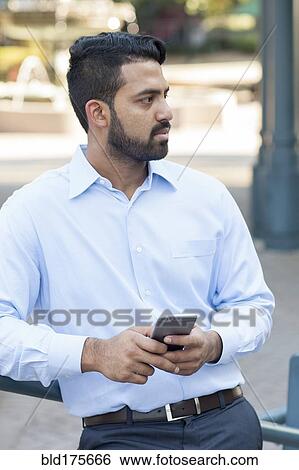 Indian businessman using cell phone in city View Large Photo Image Stock Photograph - Indian businessman using cell phone in city. Fotosearch