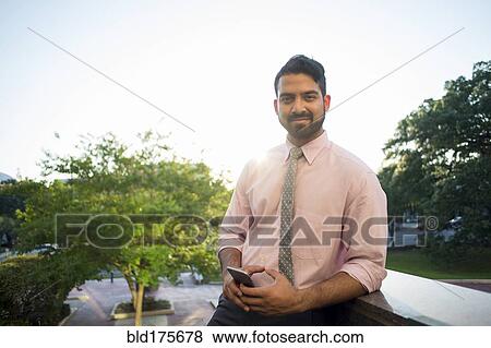 Stock Photo - Indian businessman using cell phone on steps. Fotosearch