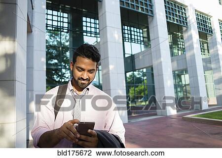 Indian businessman using cell phone outside office building View Large Photo Image Stock Image - Indian businessman using cell phone outside office building. Fotosearch