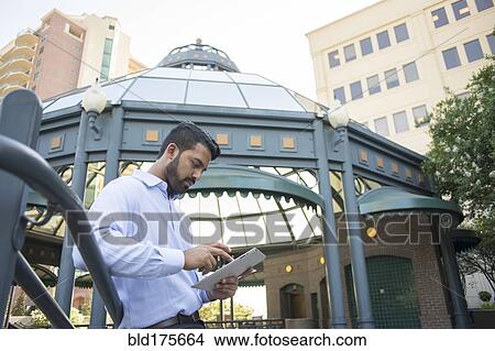 Picture - Indian businessman using digital tablet in city. Fotosearch