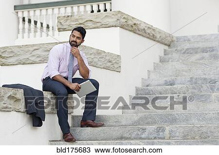 Stock Image - Indian businessman using digital tablet on steps. Fotosearch