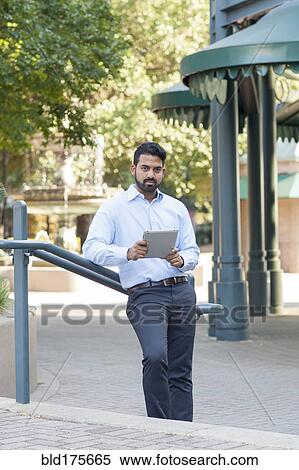 Stock Photography - Indian businessman using digital tablet outdoors. Fotosearch