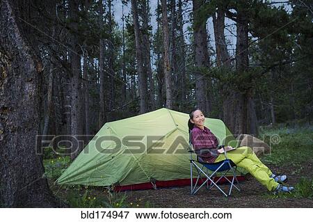 Stock Photo - Japanese woman using laptop at campsite. Fotosearch