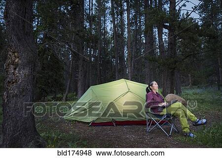 Stock Photo - Japanese woman using laptop at campsite. Fotosearch