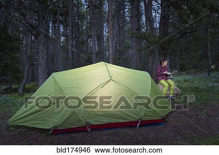 Stock Photograph - Japanese woman using laptop at campsite. Fotosearch