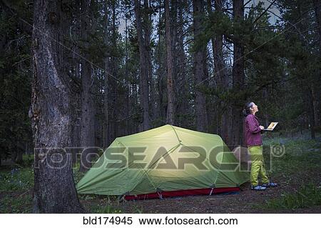 Stock Photography - Japanese woman using laptop at campsite. Fotosearch