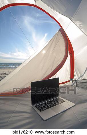Stock Image - Laptop in camping tent on beach. Fotosearch