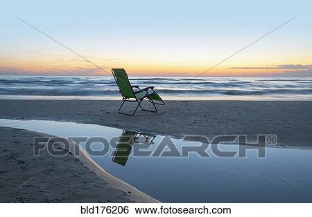 Stock Photograph - Lounge chair on beach at sunset. Fotosearch