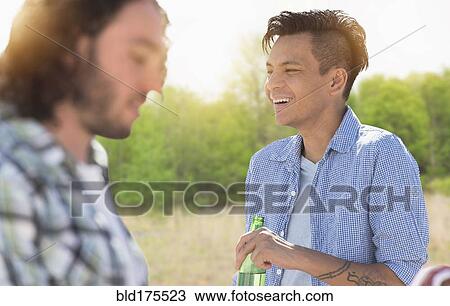 Stock Image - Man drinking beer outdoors. Fotosearch